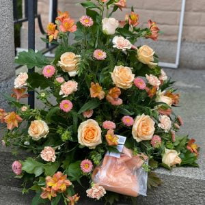 Stående begravningsdekoration i rosa och aprikosa färger